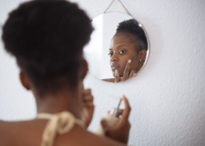 A woman applies a skincare serum to her skin, representing first-time retinol use and how to apply retinol to your face.