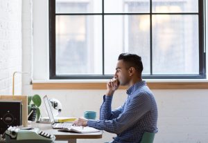 Man sits at desk working on a laptop.